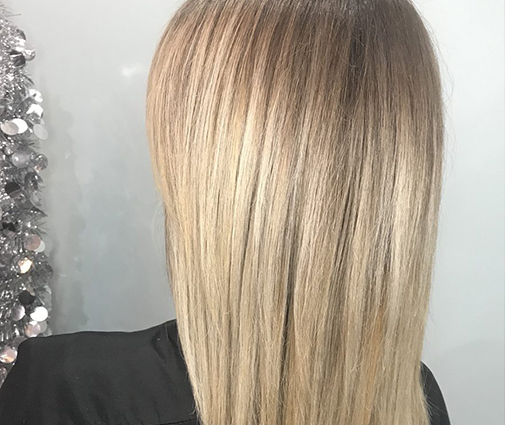 Stylist applying keratin treatment cream to sectioned hair with brush