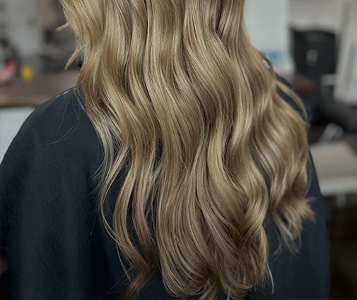 Stylist installing tape-in hair extensions on sectioned natural hair
