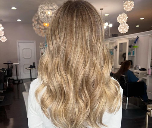 Colorist hand-painting balayage lightener onto long dark hair sections