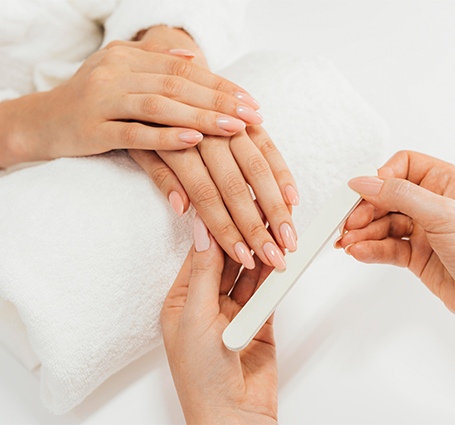 Hands resting on towel while nail technician applies gel polish
