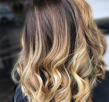 Client with freshly styled highlighted waves sitting in front of salon mirror