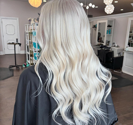 Client with bouncy, voluminous blowout hairstyle sitting in salon styling chair