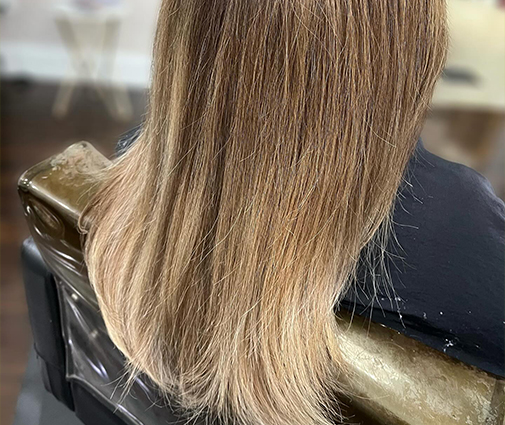 Hands blending natural hair with newly added extensions using flat iron