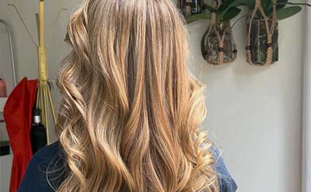 Owner smiling beside styling chair in warmly lit salon interior