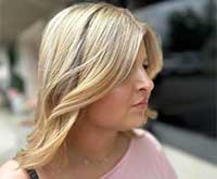 Hairstylist laughing with seated client while discussing hairstyle at mirror