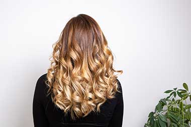 Client reclining at shampoo bowl while stylist massages scalp under running water