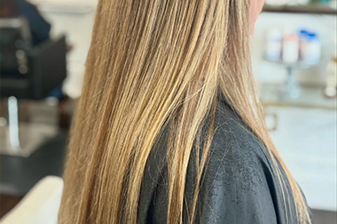 Stylist blow-drying freshly washed hair at modern salon styling chair