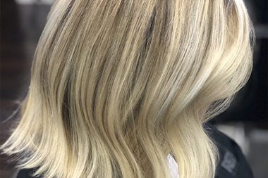 Colorist applying hair dye with brush to client’s foiled hair sections