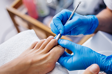 Stylist trimming client’s hair at salon station with mirrors and lights