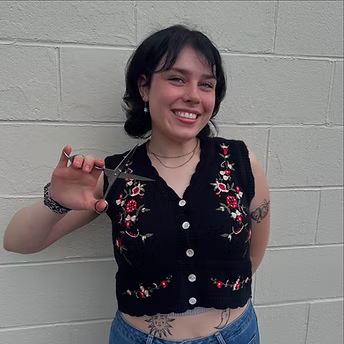 Smiling stylist posing beside client’s finished haircut near large salon mirror